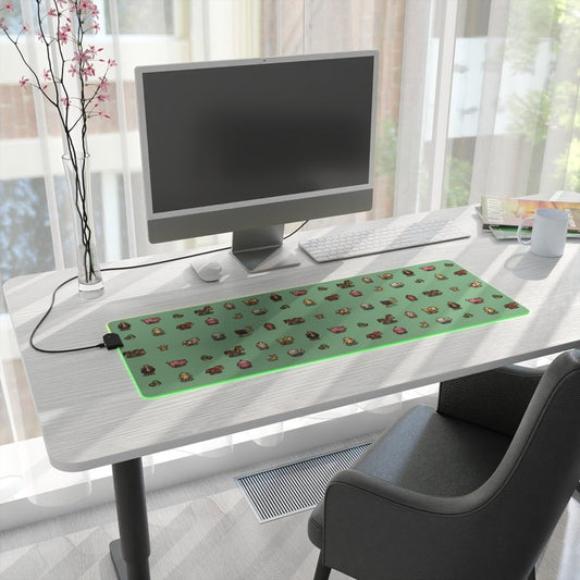 A rectangular LED gaming mouse pad featuring Stardew Valley animals against a green background sits on a desk next to a computer monitor and other office supplies.