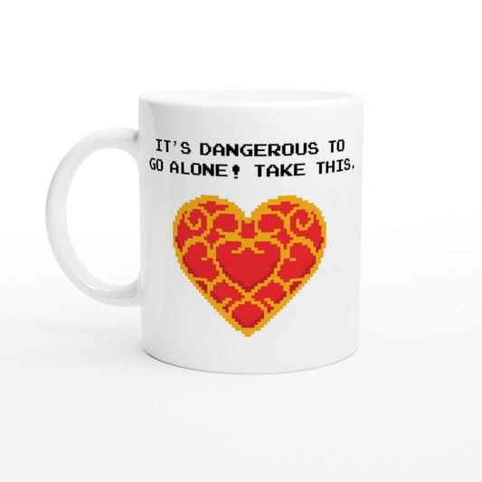 A white mug displays pixel art of a Zelda Heart Container alongside the text "It's dangerous to go alone! Take this.