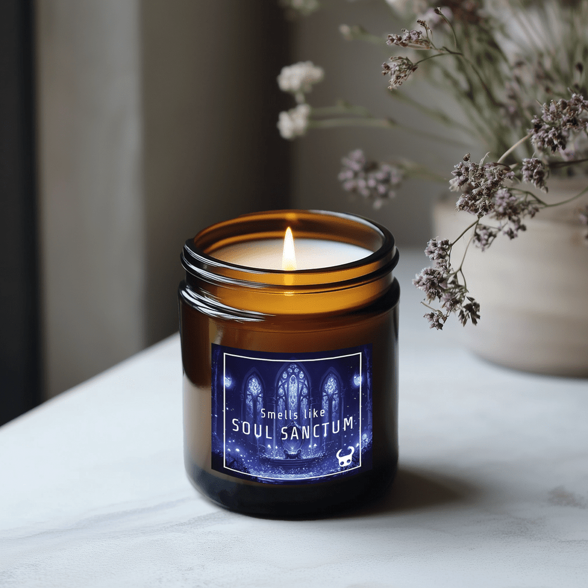 A lit candle in a brown glass jar displays a label that reads "Smells like Soul Sanctum" and features imagery inspired by the video game Hollow Knight.