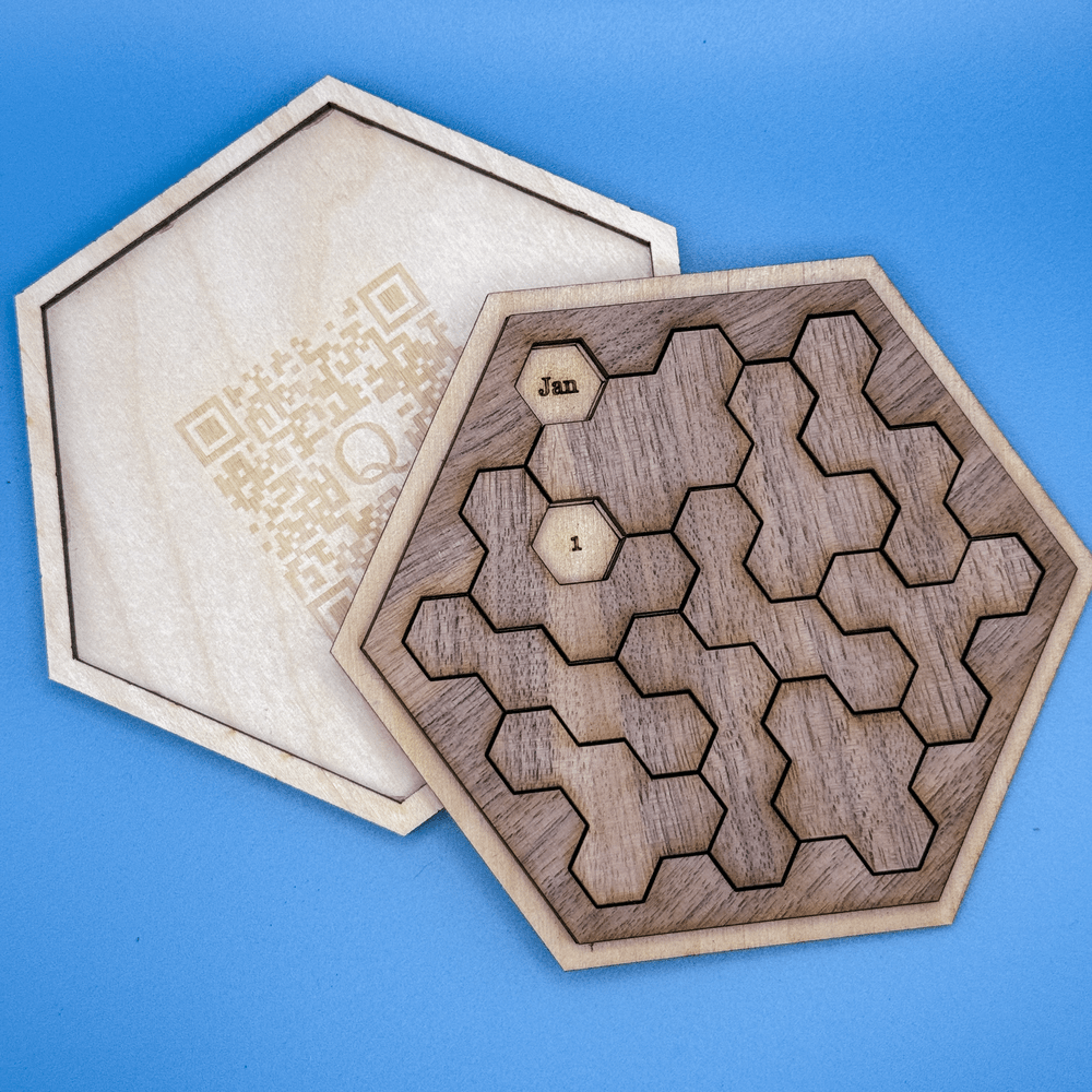 A wooden Daily Calendar Puzzle, featuring a hexagonal perpetual calendar design composed of interlocking hexominoes pieces and a QR code on its lid.