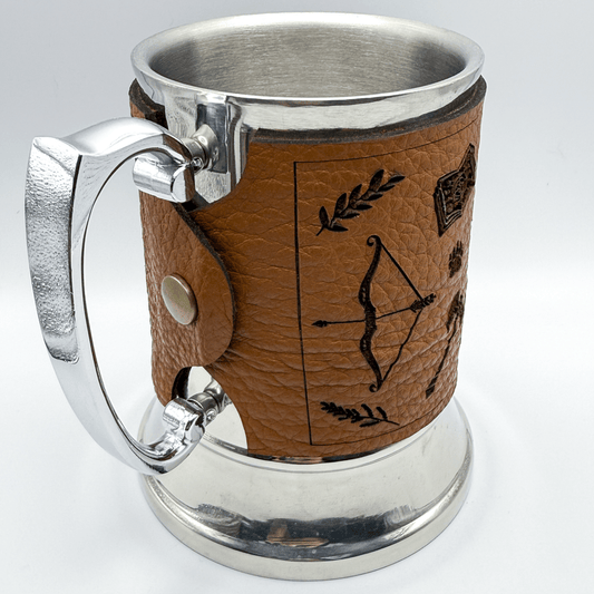 A steel beer mug is wrapped in upcycled brown leather featuring black Dungeons and Dragons-inspired designs of an arrow, bow, and shield.
