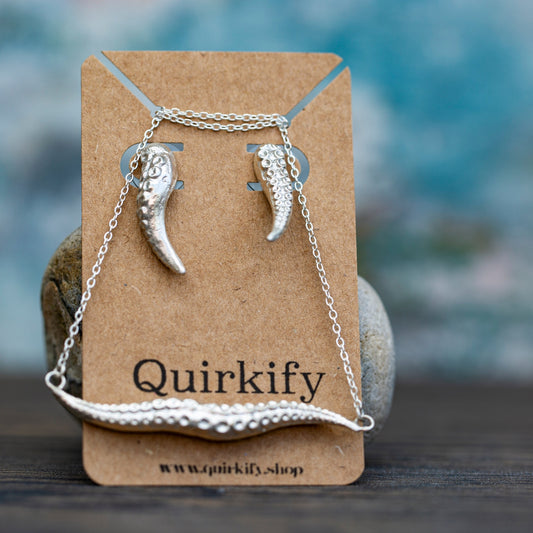 Silver necklace with tentacle-like pendants on a Quirkify branded card against a blurred natural background.