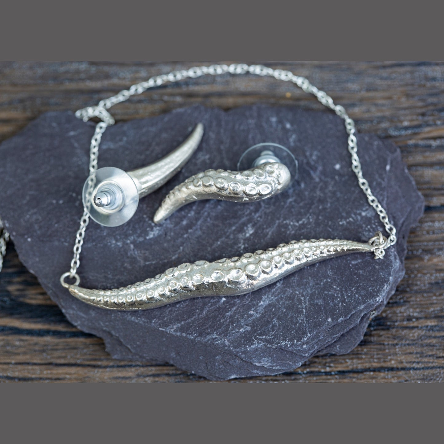 Silver necklace with kraken tentacle design on a dark stone surface