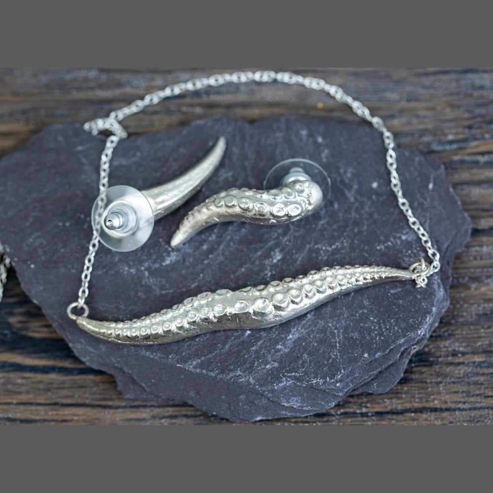Silver necklace with kraken tentacle design on a dark stone surface