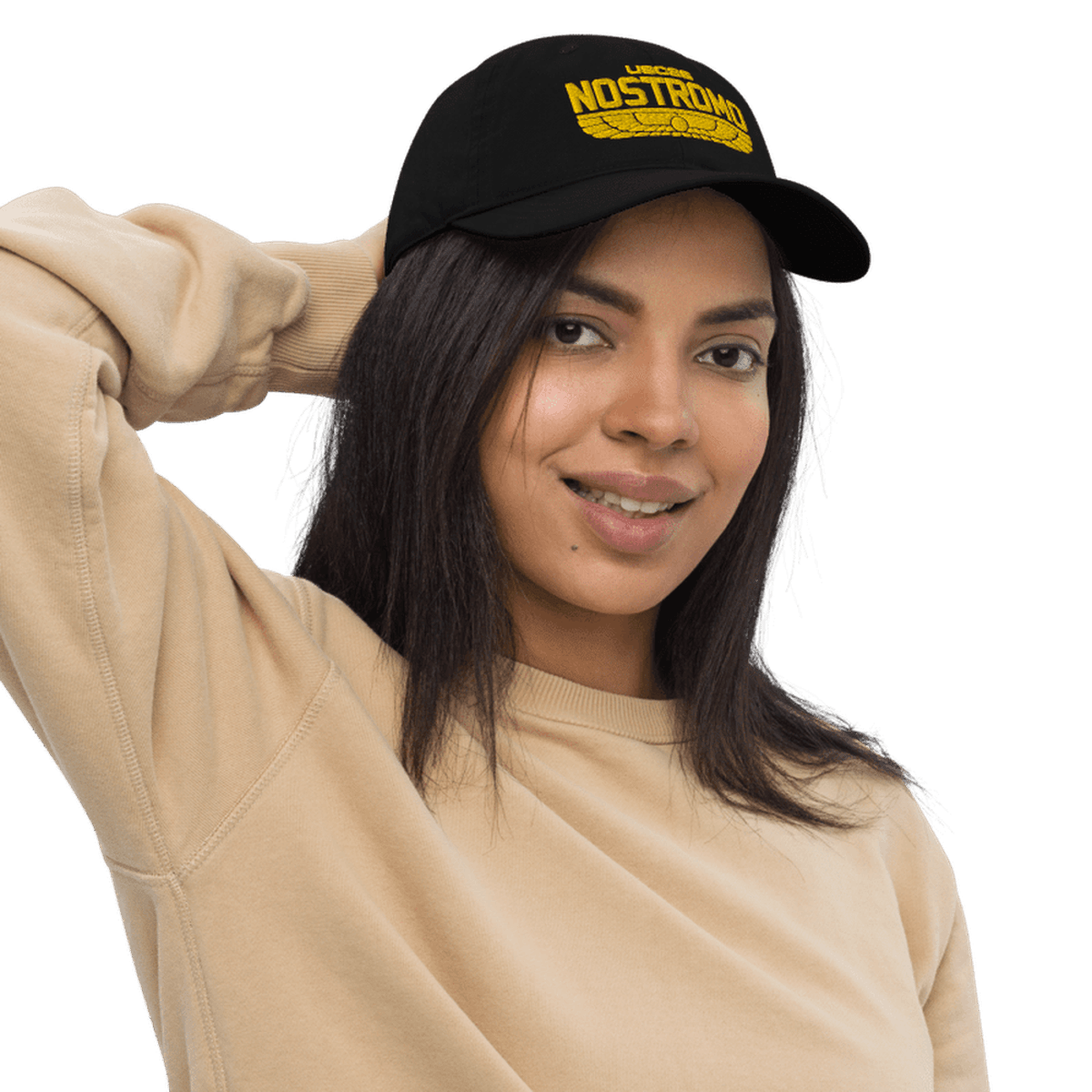 A person wearing a black baseball cap featuring yellow embroidered "NOSTRIMO" lettering and a wings-style logo referencing the Alien USCSS Nostromo.