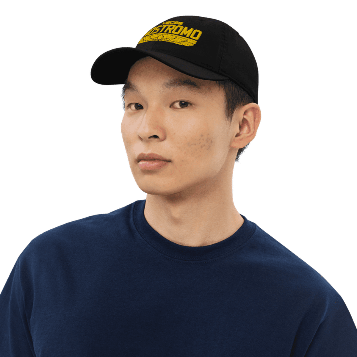 A person wearing a black baseball cap embroidered with the "NOSTROMO" logo in a wings style design, referencing the Alien USCSS Nostromo and Weyland-Yutani brands.