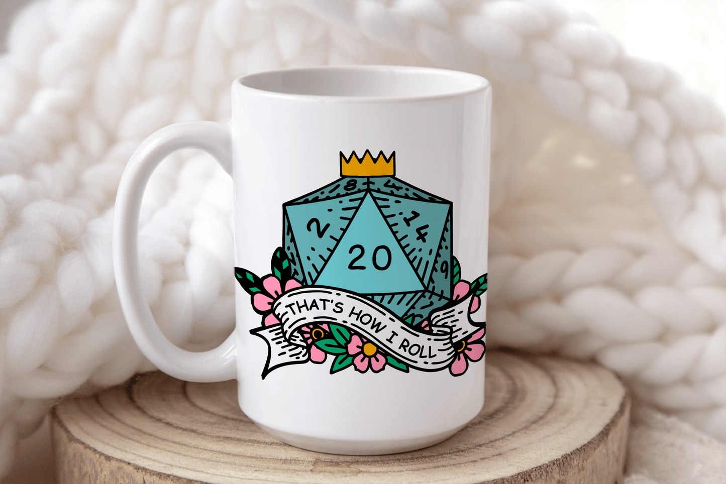A white mug displays a D&D-themed design featuring a twenty-sided die (d20) surrounded by flowers and the phrase "That's How I Roll.