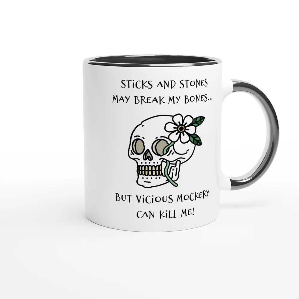 A white ceramic mug with a black rim features a drawing of a skull adorned with flowers and the phrase "Sticks and Stones May Break My Bones... But Vicious Mockery Can Kill Me!