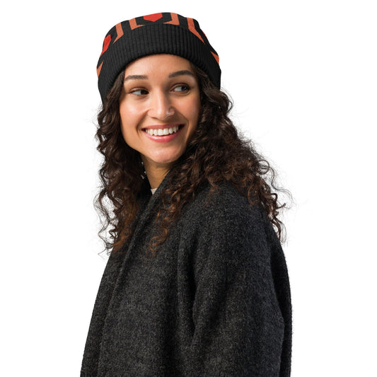 Person wearing an Overlook Hotel carpet pattern knitted beanie in orange, black and red on a white background