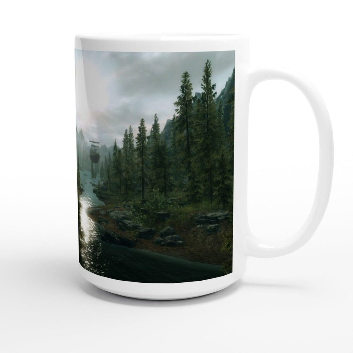 A white ceramic mug displays a landscape scene from the video game Skyrim featuring a river, forest, and mountains under an overcast sky.