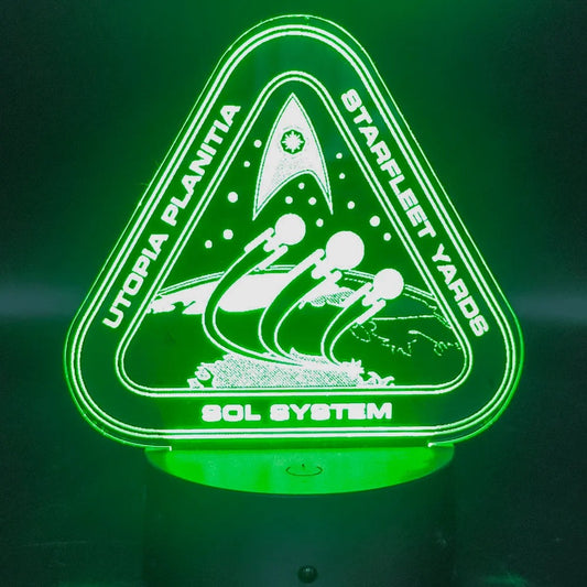 The illuminated acrylic lamp features an engraved design of the Utopia Planitia Starfleet Yards logo with spaceships and the Sol System text.