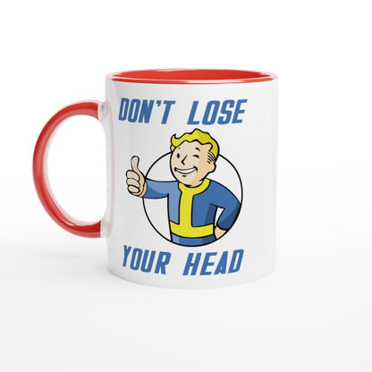 A white mug with a red handle and rim features Vault-Tec branding and cartoon character giving a thumbs up alongside the words "Don't Lose Your Head," referencing the Fallout video game.