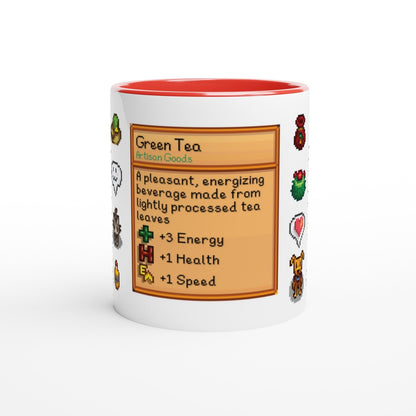A white mug displays a Stardew Drinks pattern featuring pixelated sprites and a beverage card describing Green Tea artisan goods.