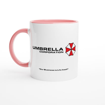 A white mug with a pink handle and rim features the Umbrella Corporation logo and the phrase "Our Business is Life Itself" referencing the Resident Evil series.