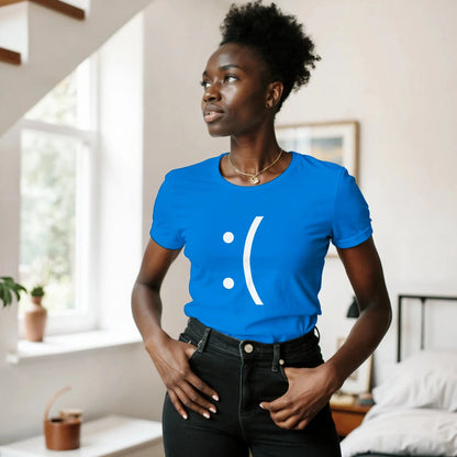 A woman wearing a blue Ladies Fit Tee displays a white pixelated sad face graphic referencing a Blue Screen of Death error.
