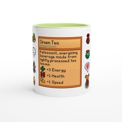 A white Stardew Drinks Pattern Mug displays a green label resembling an item card from the game, detailing Green Tea and its effects.