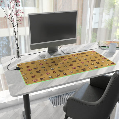 A rectangular desk mat featuring pixel art of animals from Stardew Valley sits on a white desk illuminated by an LED light around its perimeter.