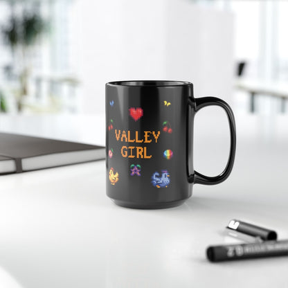 A black coffee mug displays pixel art sprites / graphics from Stardew Valley including a heart, cherries, a prismatic shard, a stardrop, and butterflies.