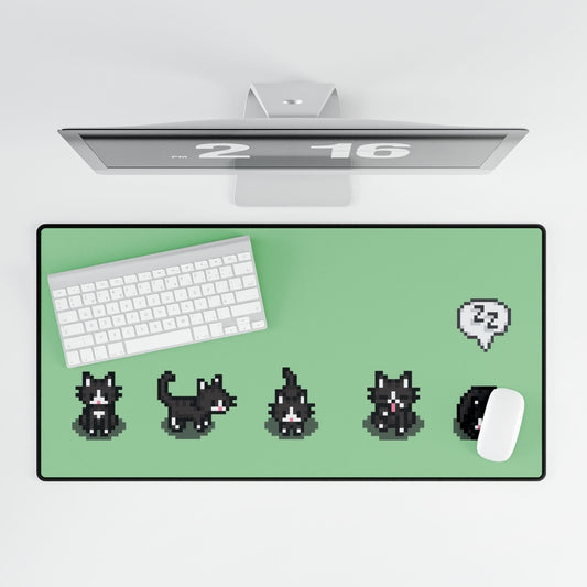An extra large desk mat features a black and white pixelated cat pattern reminiscent of Stardew Valley alongside a keyboard, mouse, and computer monitor.