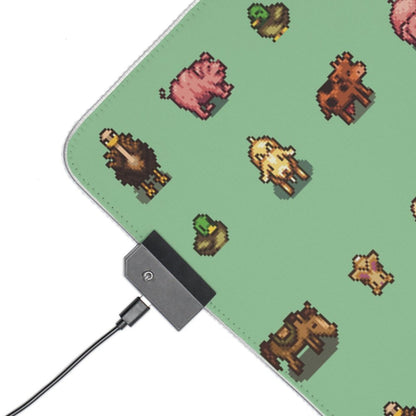 A rectangular LED gaming mouse pad features pixelated images of Stardew Valley animals against a green background.