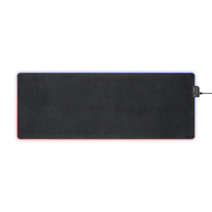 A rectangular black desk mat features LED lighting along its edges in red, blue, and purple.