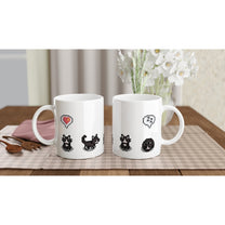 A white mug displays pixelated illustrations of tuxedo cats and emotes referencing the Stardew Valley computer game.
