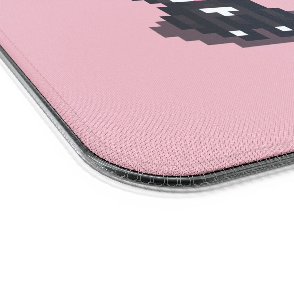 A close-up view of the textured pink surface and stitched edge of a Stardew Valley Tuxedo Cats LED Cosy Gaming Desk Mat.