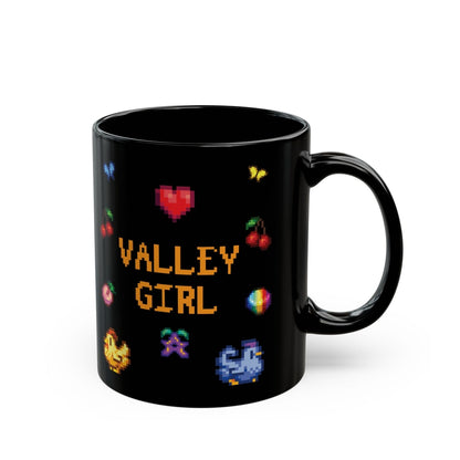 A black coffee mug displays pixel art sprites / graphics from Stardew Valley including a heart, cherries, a prismatic shard, a stardrop, and butterflies.