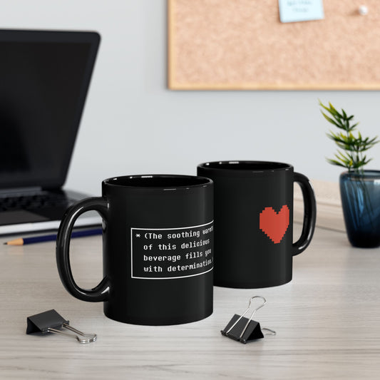 Two black Undertale mugs sit on a desk, one displaying white text and the other featuring a pixelated red heart graphic.