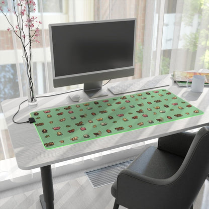 A rectangular LED gaming mouse pad featuring Stardew Valley animals on a green background sits on a desk next to a computer and other office supplies.
