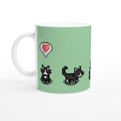 A white mug displays pixelated graphics of tuxedo cats and a heart emote referencing the Stardew Valley computer game.
