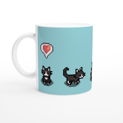 A white mug displays pixelated graphics of tuxedo cats and a heart emote inspired by the Stardew Valley computer game.