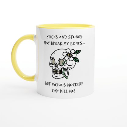 A white mug with a yellow handle features text referencing "Sticks and Stones" and "Vicious Mockery," along with an illustration of a skull adorned with a flower.