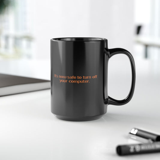 Black mug with 'It's now safe to turn off your computer' from Windows 95 / 98, on a desk with office items