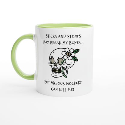 A white mug with a light green handle and rim features a skull illustration adorned with flowers and text referencing "Sticks and Stones" and "Vicious Mockery," inspired by Dungeons & Dragons.