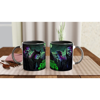 A black mug displays character portraits of Laszlo, Nadja, Nandor, Guillermo, and Colin Robinson from What We Do In The Shadows alongside stylized text.