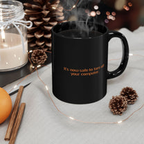A black mug featuring the Windows 95/98 text It's now safe to turn off your computer sits on a cloth next to a candle and pinecones.