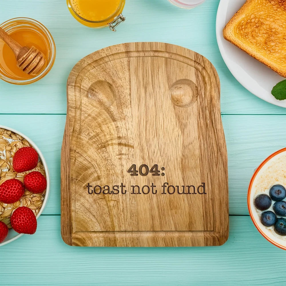 A rubberwood breakfast board featuring the engraved text 404: toast not found sits on a light blue wooden surface surrounded by breakfast items.