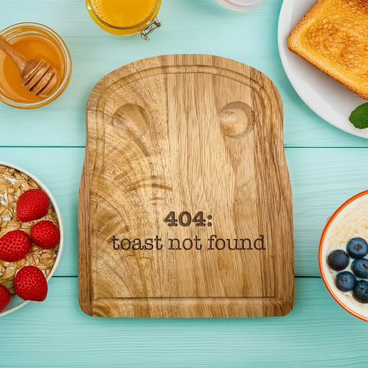 A rubberwood breakfast board featuring the engraved text 404: toast not found sits on a light blue wooden surface surrounded by breakfast items.