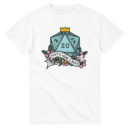 A white t-shirt displays a colorful illustration of a D20 die surrounded by flowers and a banner reading "That's How I Roll," referencing the tabletop game Dungeons & Dragons.
