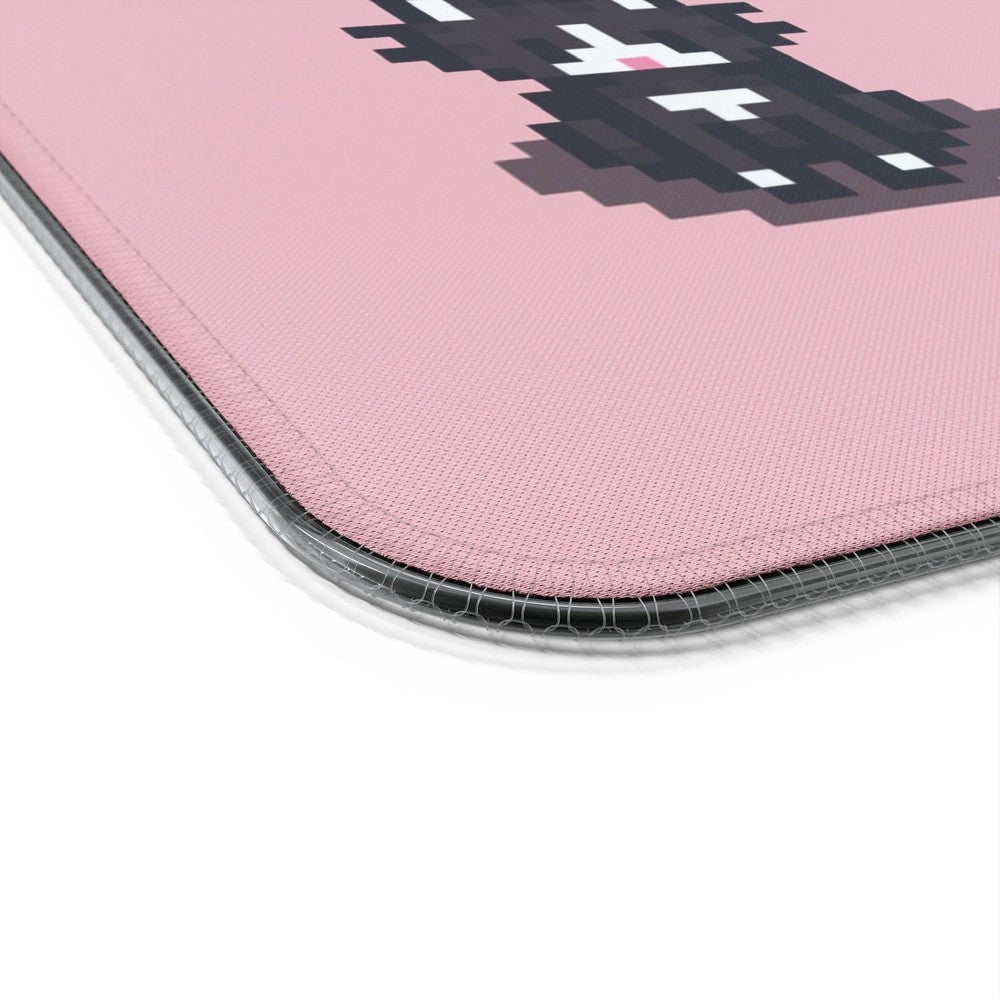 A close-up view of the textured pink surface and stitched edge of a Stardew Valley Tuxedo Cats LED Cosy Gaming Desk Mat.