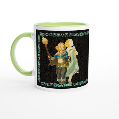 A white mug with a green handle and rim features an illustration of Link from The Legend of Zelda: Tears of the Kingdom alongside another character against a black background patterned with Sheikah script.