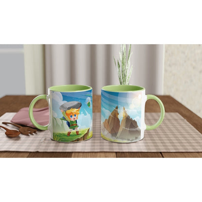 A green mug displays a chibi Link from The Legend of Zelda holding a rock and standing on grass, alongside an image of mountains.