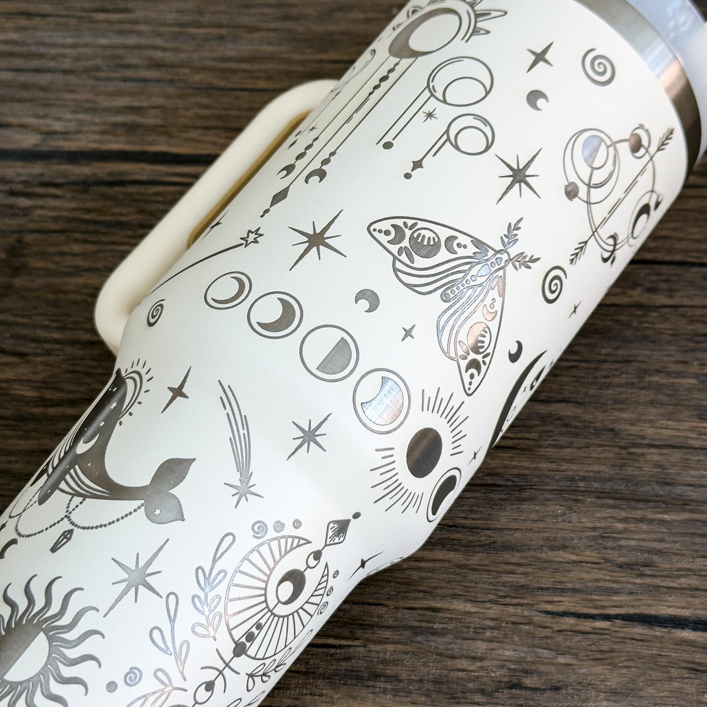 A white engraved tumbler features a celestial design of stars, moons, crystals, and other witchy boho imagery.
