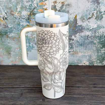 A white 40oz tumbler features a unique engraved botanical design of floral dahlias covering its surface.