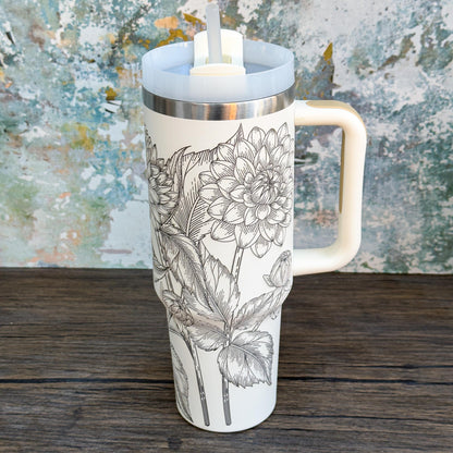 A white Floral Dahlias 40oz Tumbler features a detailed engraved botanical design of dahlia flowers and leaves.