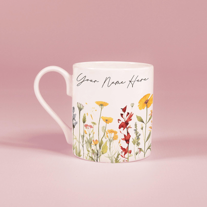 A white china mug features a watercolour floral design of wildflowers and personalized text reading "Your Name Here".