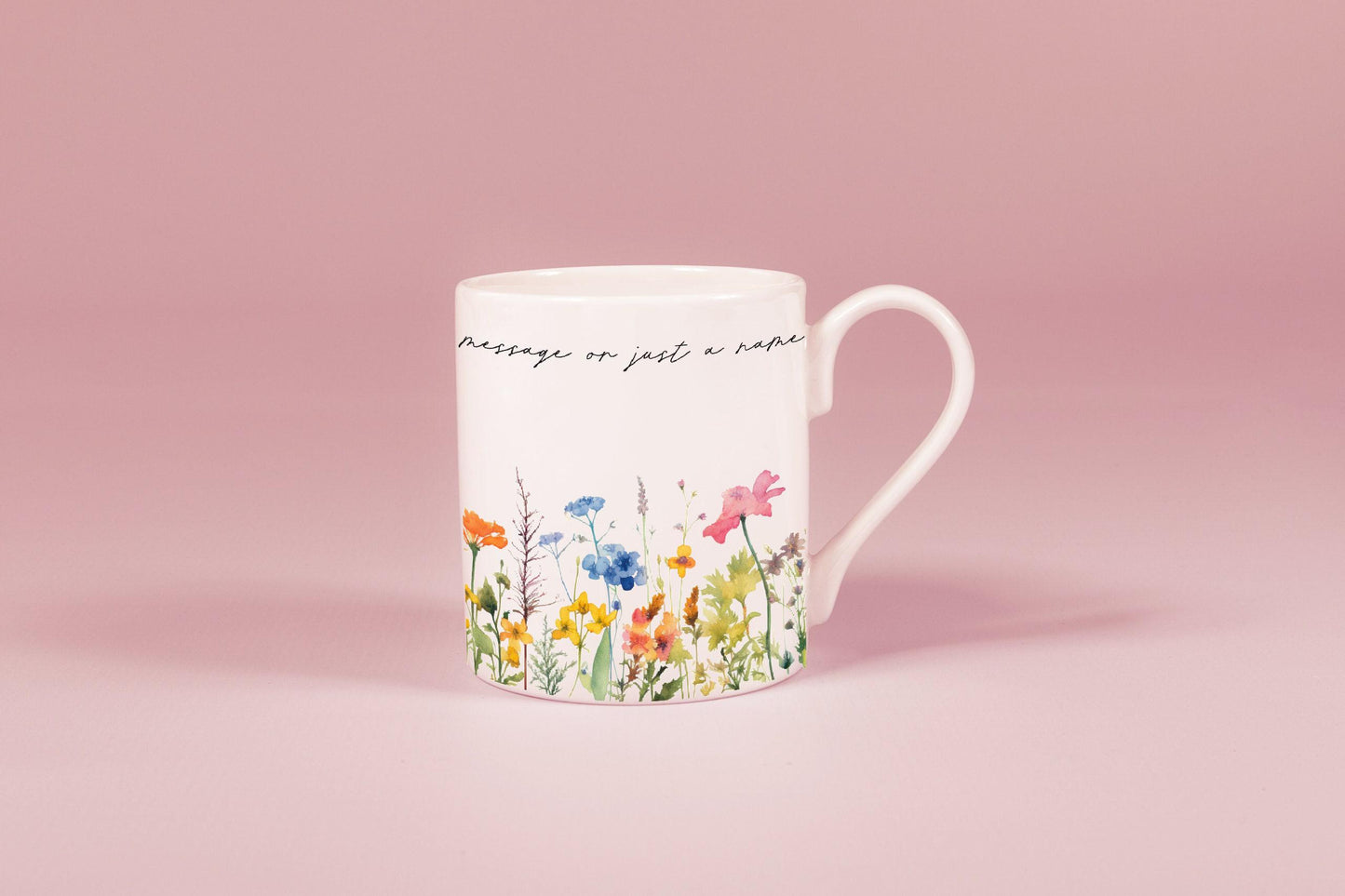 A white china mug features a watercolour floral design of wildflowers along with handwritten script reading "message or just a nap".