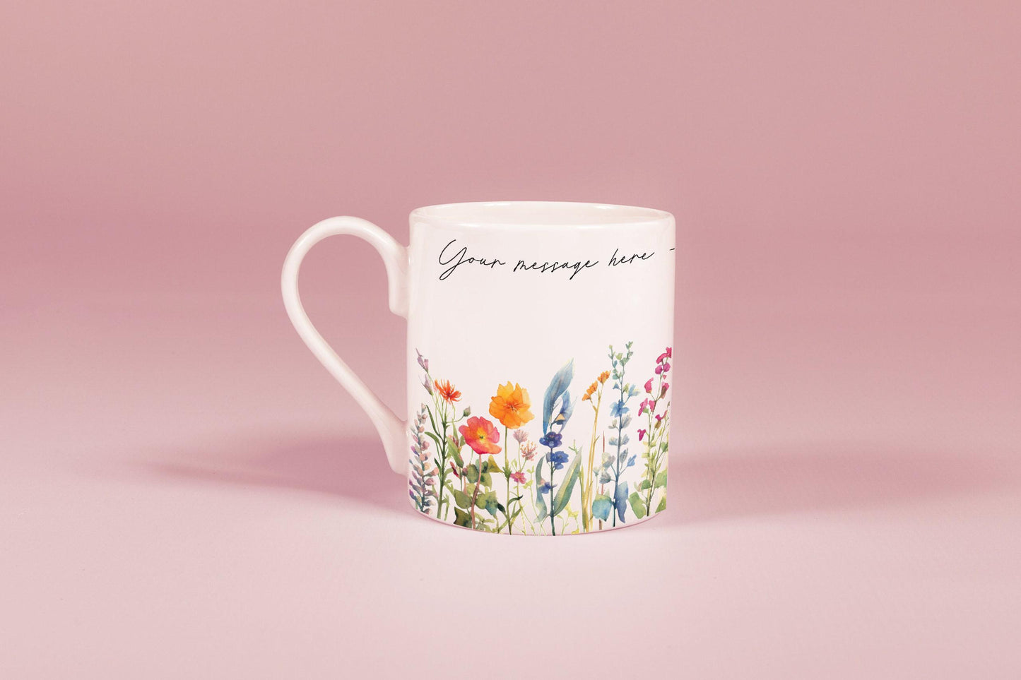 A white china mug features a watercolour floral design of wildflowers along with the text "Your message here".
