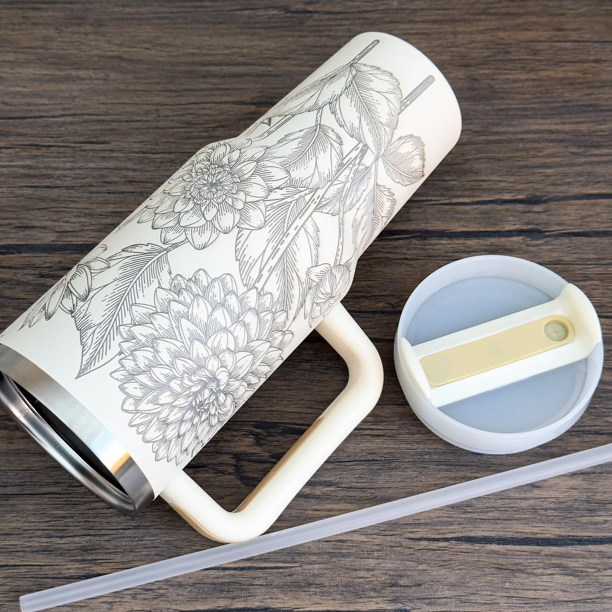 A cream-colored Floral Dahlias 40oz Tumbler features a unique engraved botanical design of dahlia flowers and foliage.